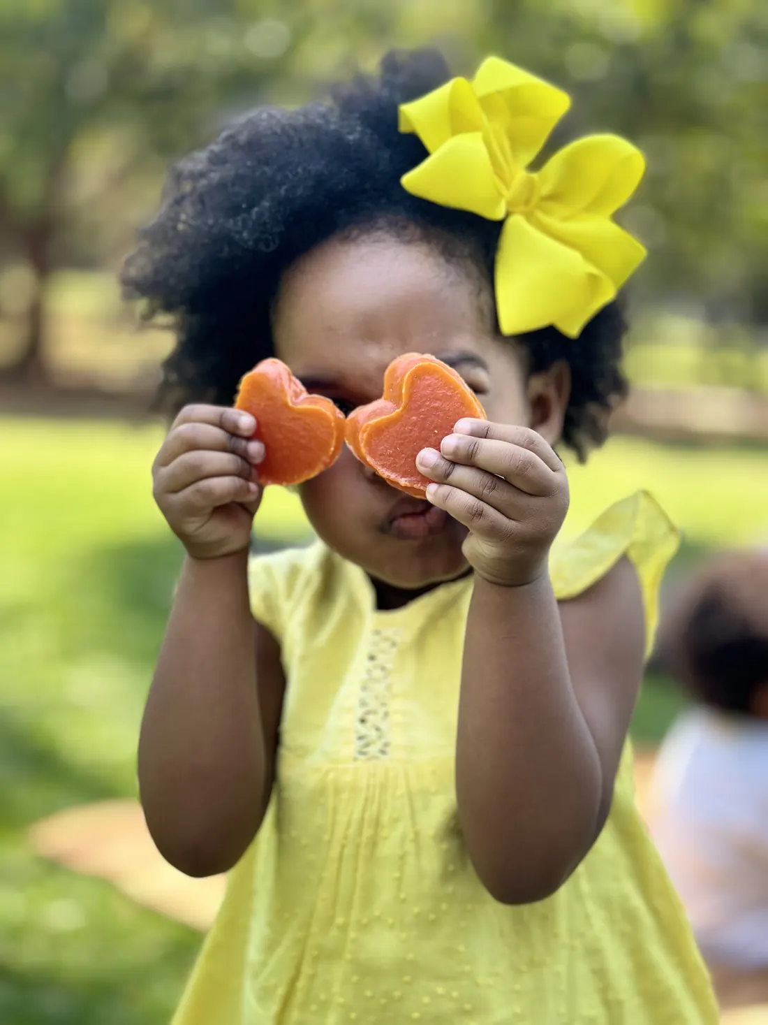 Menina segurando dois doces de batata doce em formato de coração na frente dos olhos